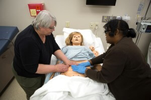 Nursing professor Laura Wallace helps nursing student Emilie Miller run through procedures on the new OB simulator.