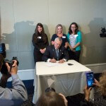 Governor Nathan Deal signs House Bill 62 into law during the Atlanta Press Club lunch Wednesday, April 29, in font of Brenau occupational therapy alumnae Rachel Strazynski, Shelby Wrenn and Allison Guisasola. HB 62, which helps special needs children of military personnel by lifting a one-year residency requirement before students can receive benefits, started as a class project the Brenau students worked on and pitched to Representative Kevin Tanner as they earned their graduate degrees.