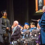 Brenau's Ann Marie Holman, a graduate of the masters in gerontology program, walks to meet Dr. Schrader on the stage in Pearce Auditorium.