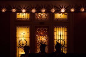 Students and Provost Nancy Krippel, left, are silhouetted in front of the windows of the Pearce Auditorium during the Brenau University College of Health Sciences Graduate Hooding Ceremony on Thursday, May 5, 2016. (AJ Reynolds/Brenau University)