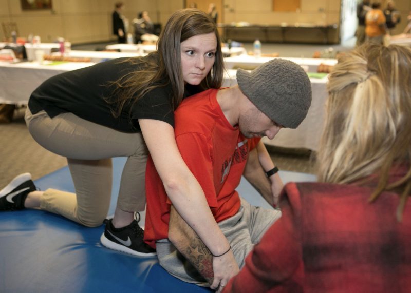 Brenau University occupational therapy graduate student Callie Setzer, left, listens to instructions from Shepherd Center OT Katie Kimball, right, as she prepares to work with patient Josh Hill. (Phil Skinner for Brenau University)