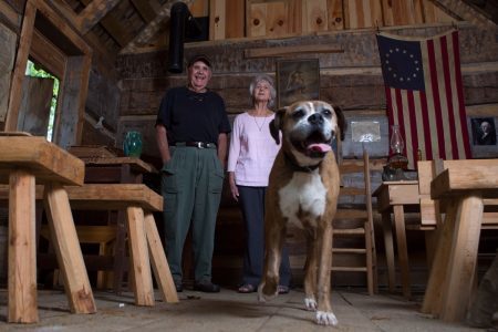 Joyce Lott, WC '59, right, her husband, Tom, and their dog Chloe pose for a photo inside the church and one-room schoolhouse at the village on their farm in Cleveland, Ga. (AJ Reynolds/Brenau University)