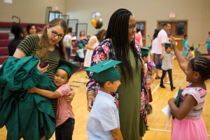 Olivia McFerrin, a senior early childhood education major, left, gets a hug from a student while Sasha Stovall, WC '15, during the commencement ceremony for the RISE Program on Friday, July 14, 2017 at Fair Street School. (AJ Reynolds/Brenau University)