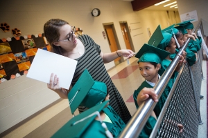Olivia McFerrin fixes a students cap during the commencement ceremony for the RISE Program on Friday, July 14, 2017 at Fair Street School. (AJ Reynolds/Brenau University)