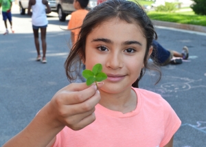 Ashley Santana holds up a four-leafed sprout she picked during the RISE Summer Program. RISE is a collaborative six-week summer program created by community partners that reduces summer learning loss among low-income children through interactive programming.