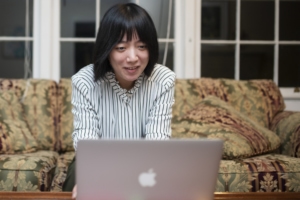 Woman sits at a laptop on a couch