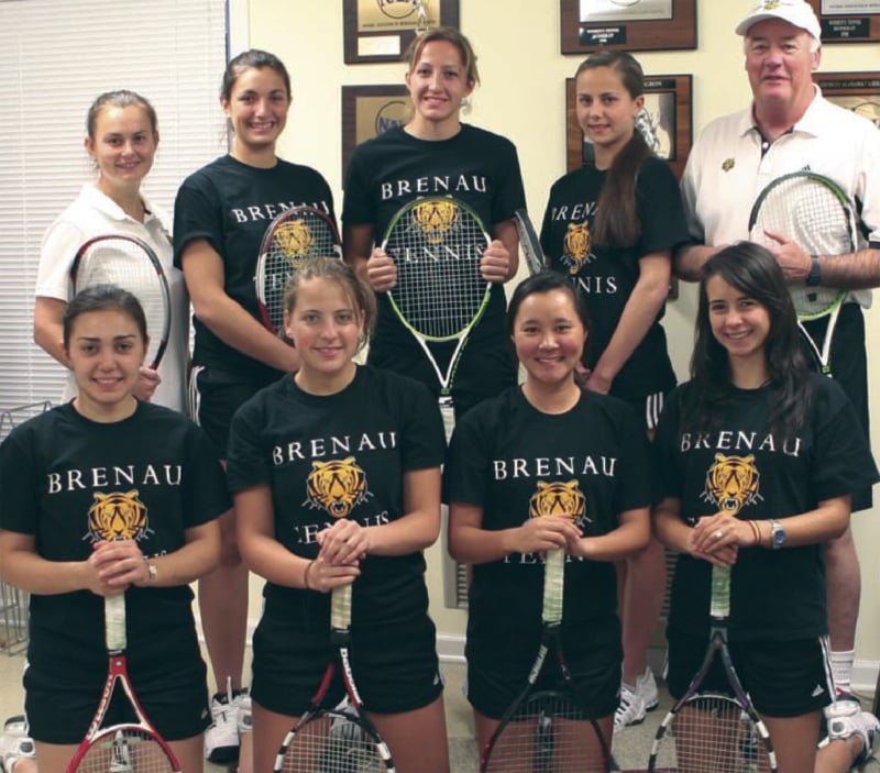 Young Women holding tennis racquets and standing with their older male coach
