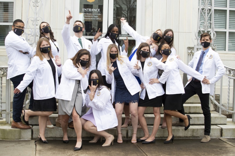 PA students in white coats and masks posing