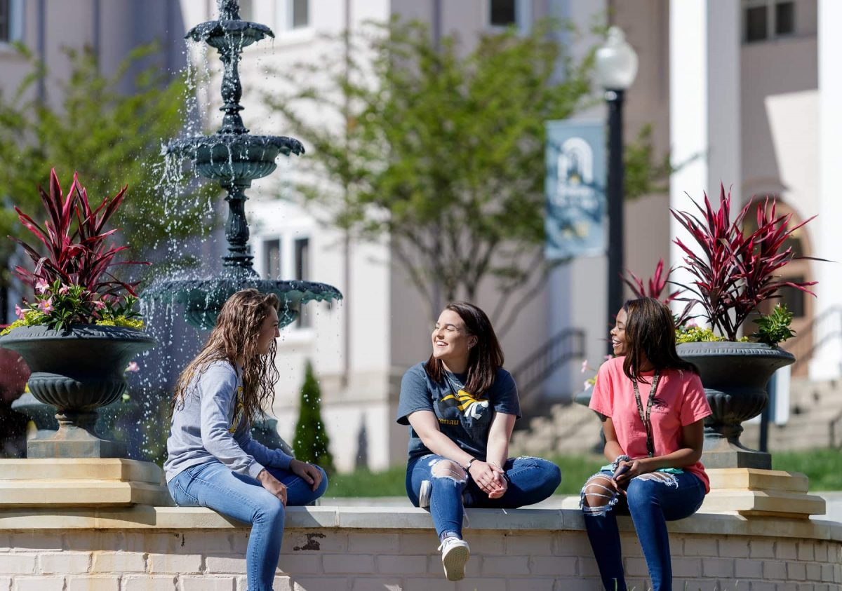 Students sit together at the fountain.